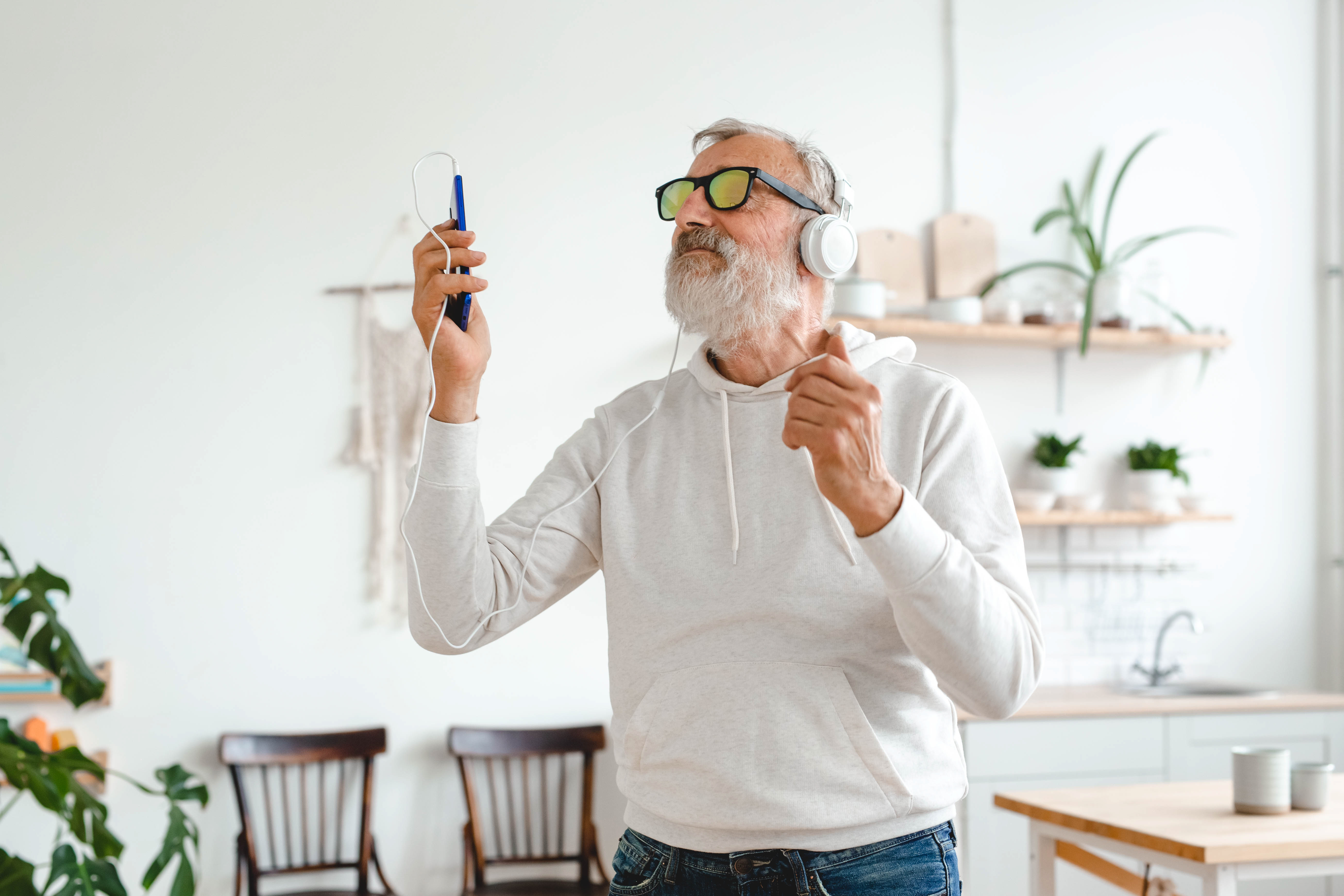 Happy senior man dancing while listening to music with headphones - active old people and enjoyment